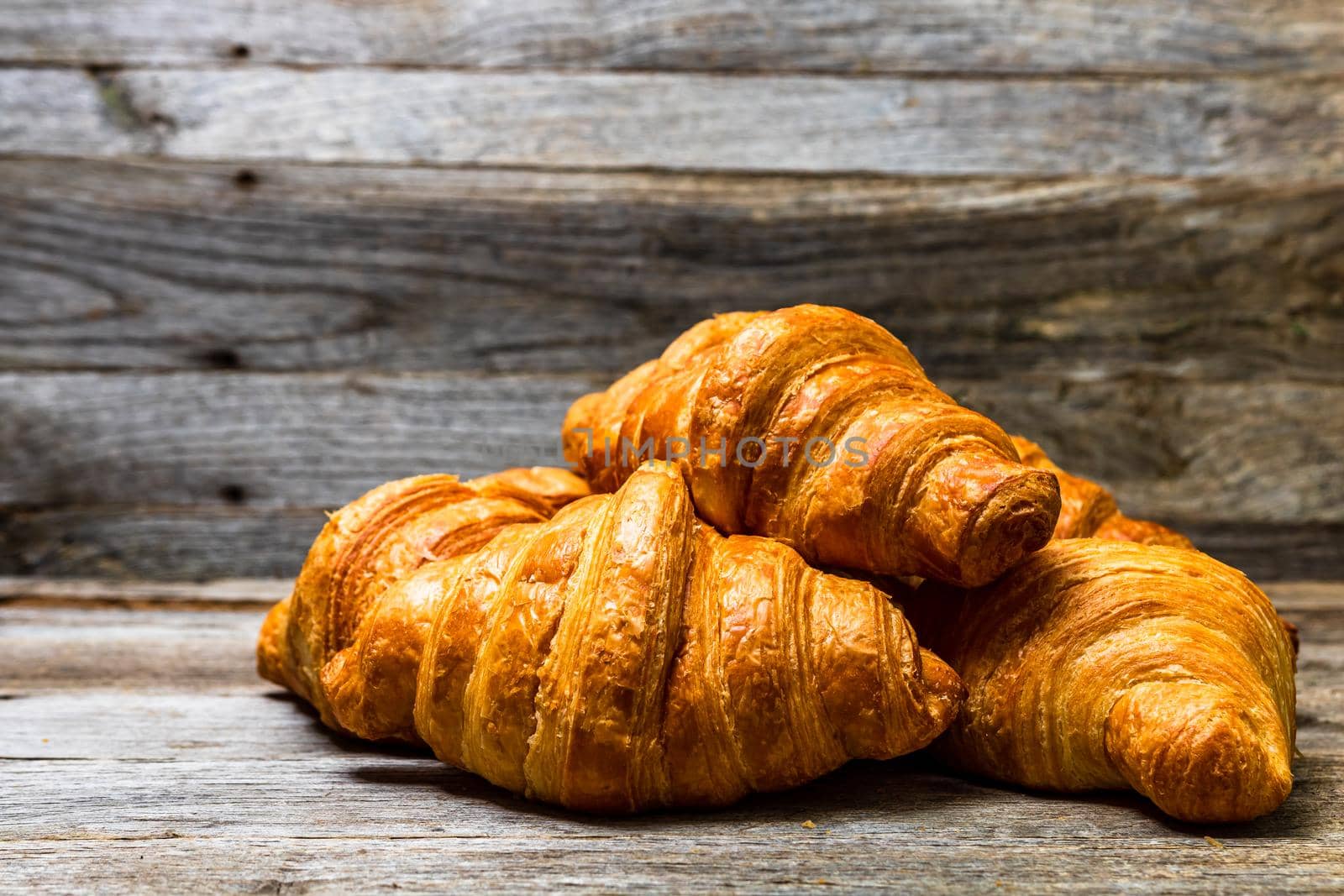 Delicious, fresh croissants isolated on wooden board. French breakfast concept. by vladispas