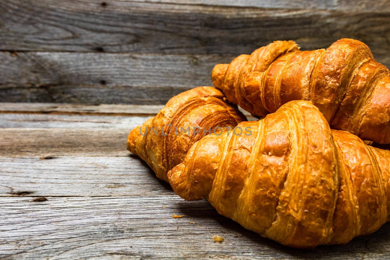 Delicious, fresh croissants isolated on wooden board. French breakfast concept. by vladispas