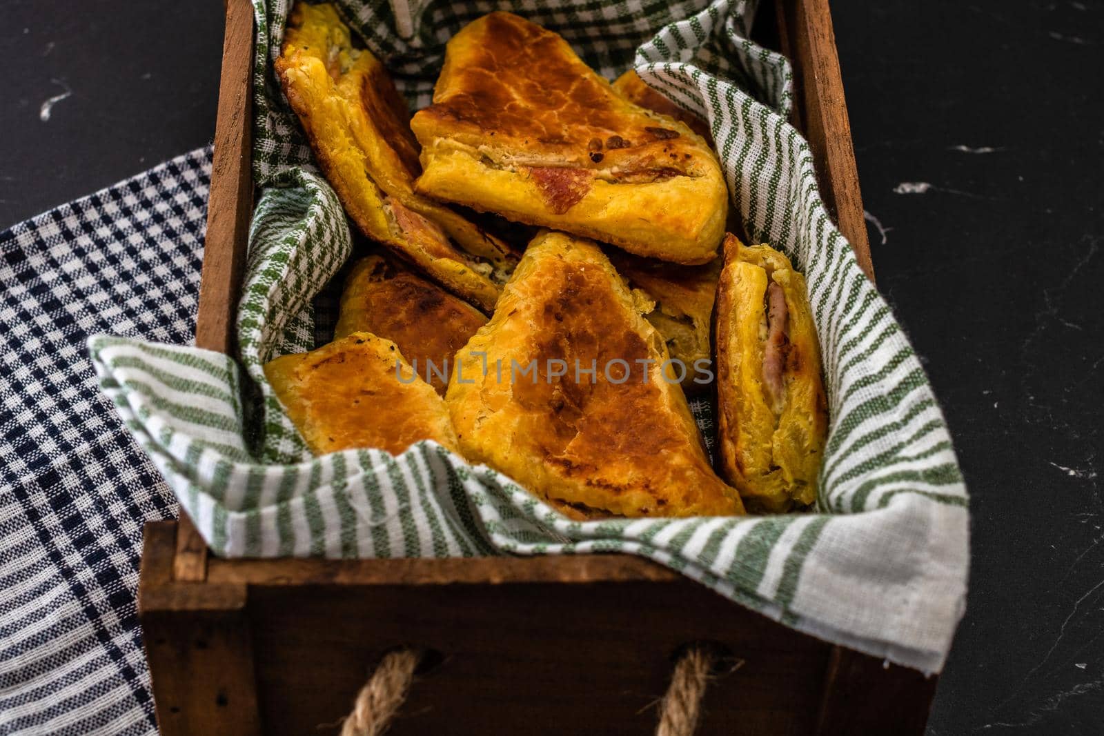 Freshly baked homemade ham and cheese puff pastry in a rustic crate.