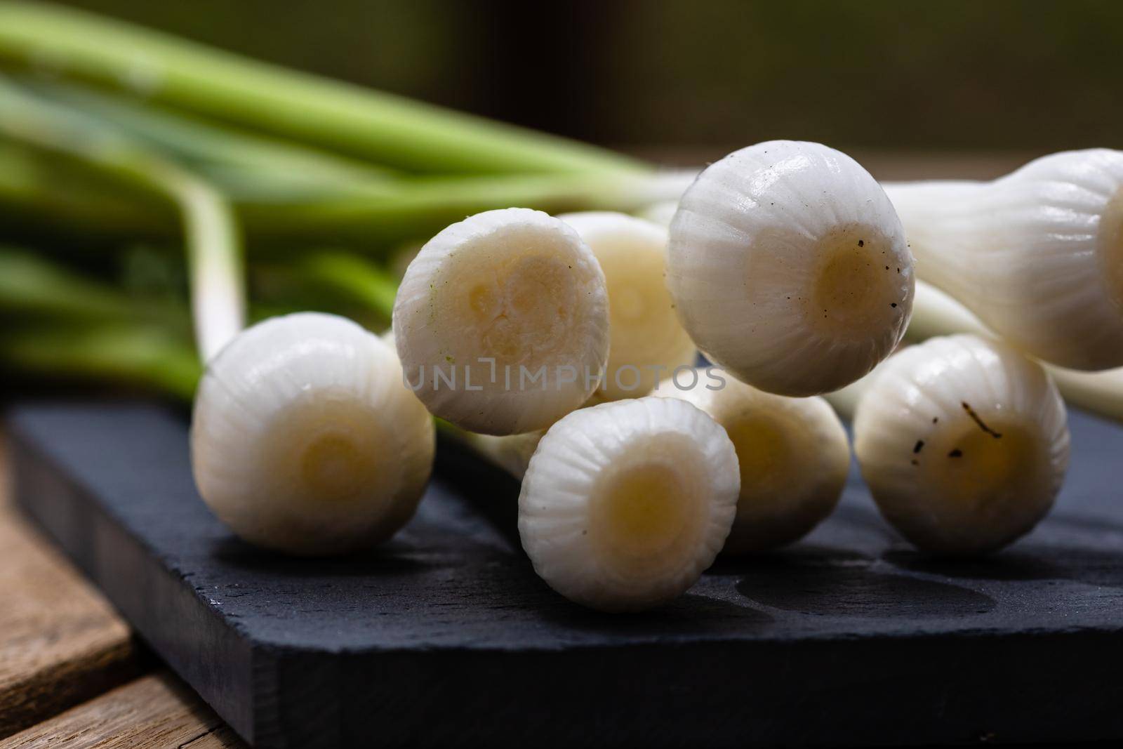 Close up of details of fresh green onions (scallion) on a cutting board isolated.