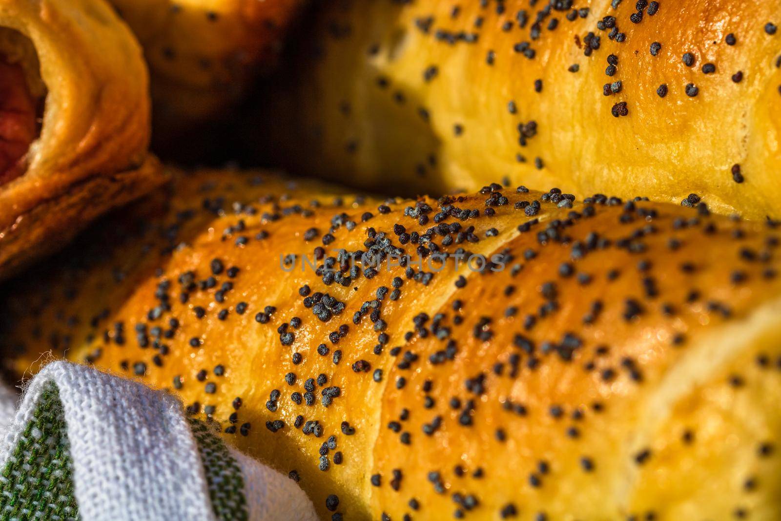 Close up on details of sausages baked in dough sprinkled with salt and poppy seeds. Sausages rolls, delicious homemade pastries.