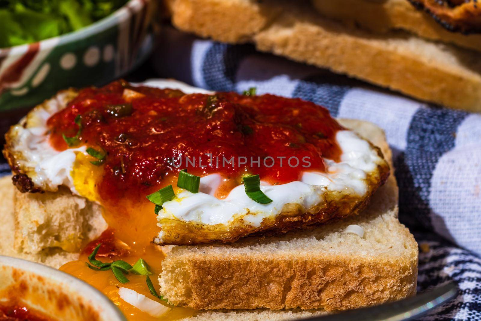 Close up of fried egg with tomato sauce and garlic on toast bread isolated.