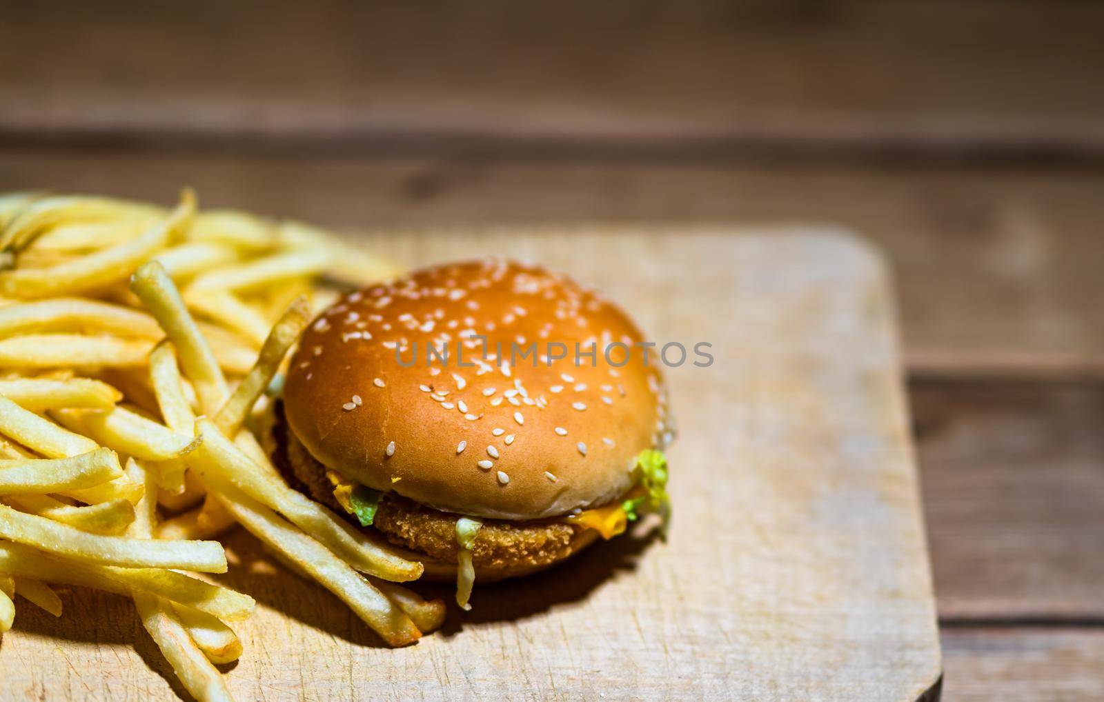 French fries and chicken burger on a wooden table. Food, junk food and fast food concept by vladispas