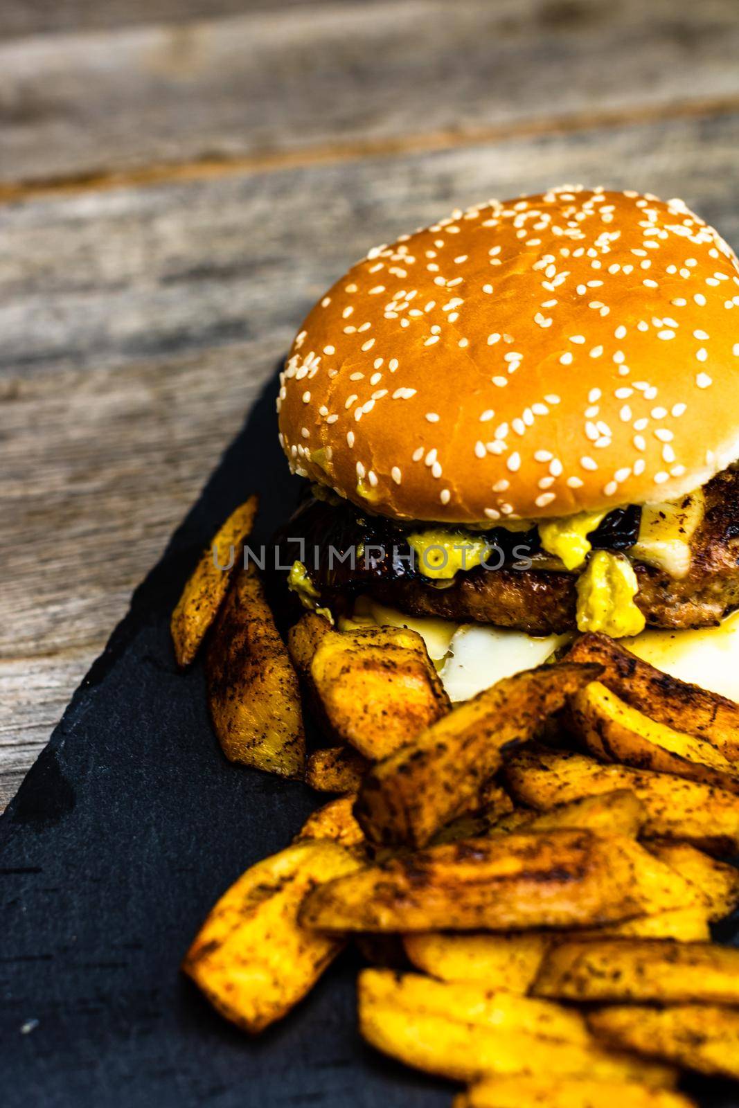 Homemade fresh tasty cheese burger and fried potatoes on a wooden table by vladispas