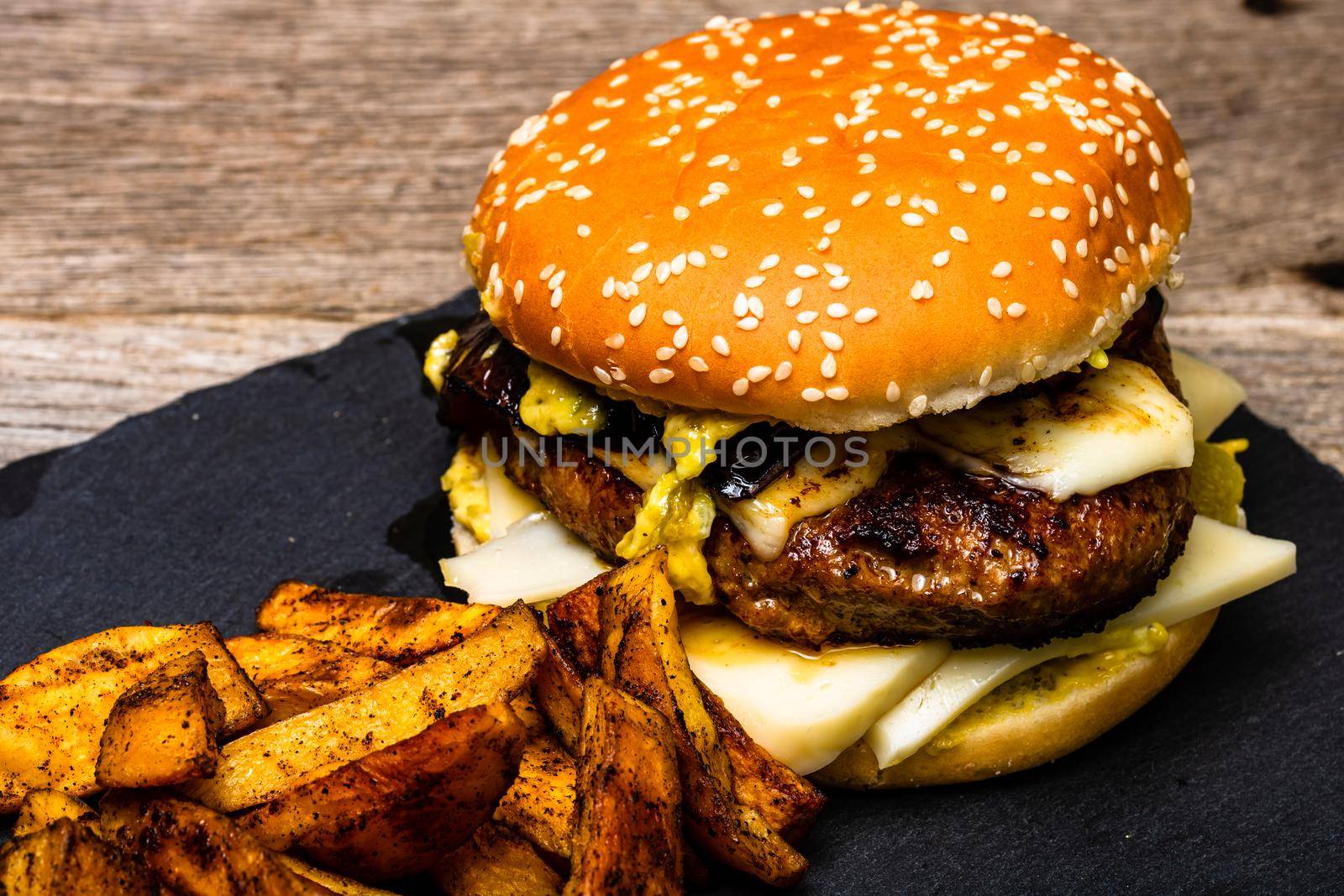 Homemade fresh tasty cheese burger and fried potatoes on a wooden table by vladispas