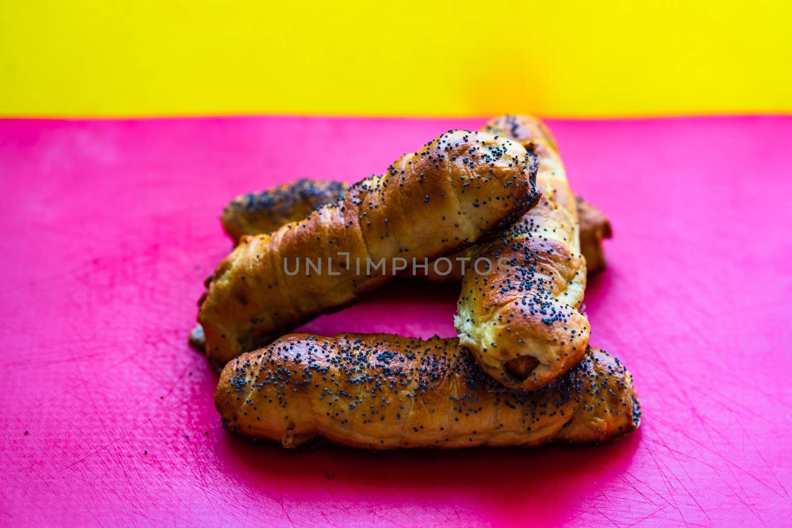 Close up of sausages baked in dough sprinkled with salt and poppy seeds. Sausages rolls, delicious homemade pastries isolated. by vladispas