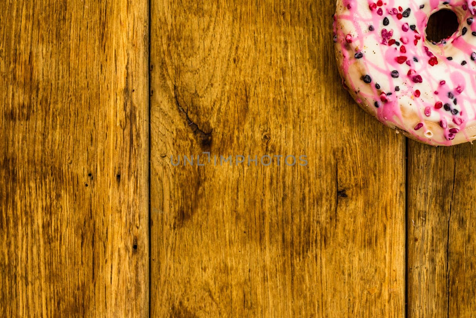 Colorful donuts on wooden table. Sweet icing sugar food with glazed sprinkles, doughnut with chocolate frosting. Top view with copy space by vladispas