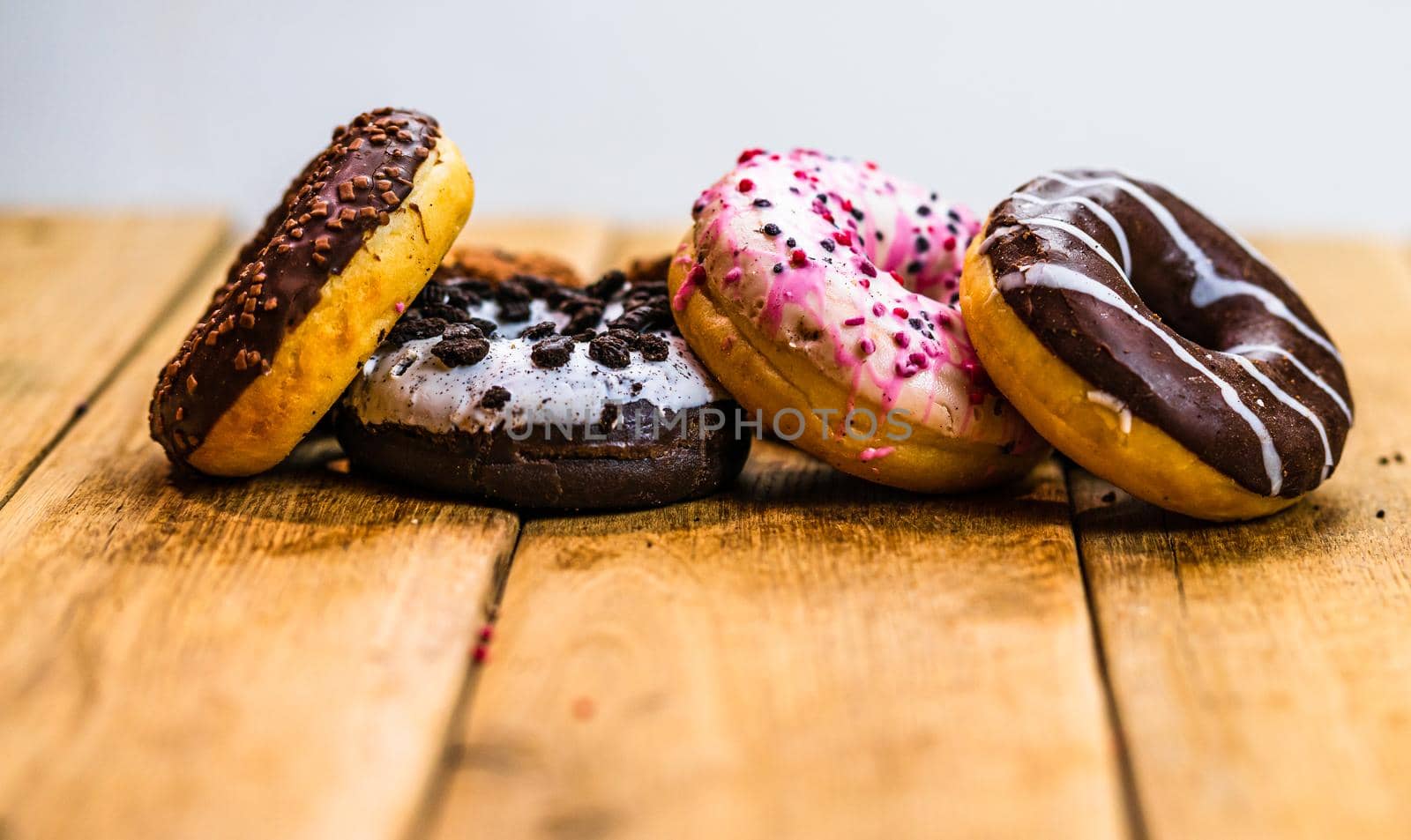 Colorful donuts on wooden table. Sweet icing sugar food with glazed sprinkles, doughnut with chocolate frosting. Top view with copy space by vladispas