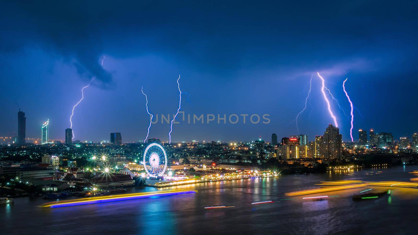 Thunder storm lightning strike on the dark cloudy sky over business building area in Bangkok,Thailand. Bangkok is the capital of Thailand and also the most populated city. by Nuamfolio