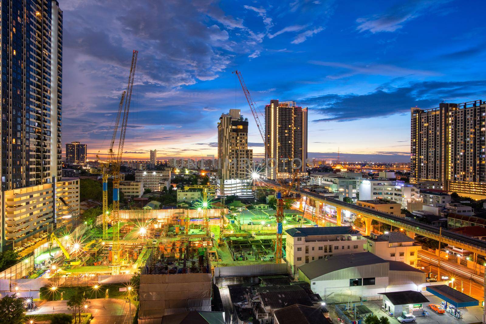 Construction site with backhoe and dump truck busy operate in beginning of building new complex building project in Thailand. by Nuamfolio