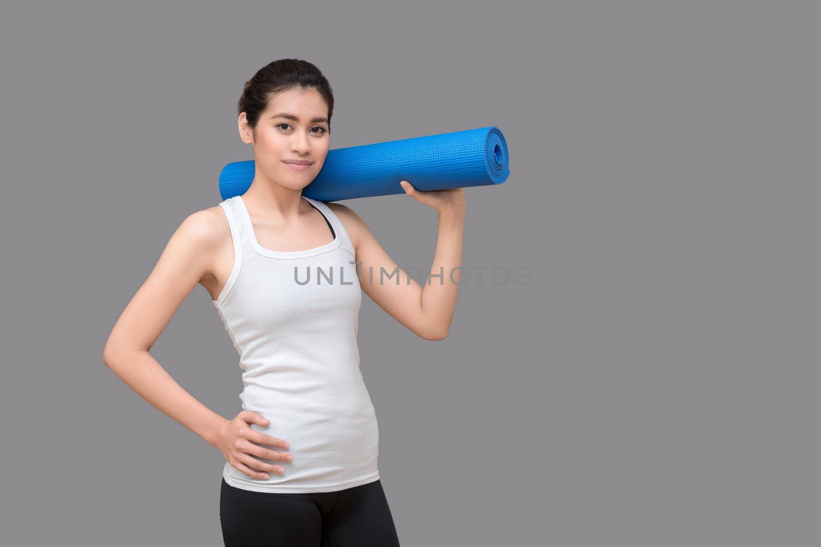 Young asian woman holding her yoga mat at healthy sport gym. Yoga and meditation have good benefits for health. Photo concept for Yoga Sport and Healthy lifestyle