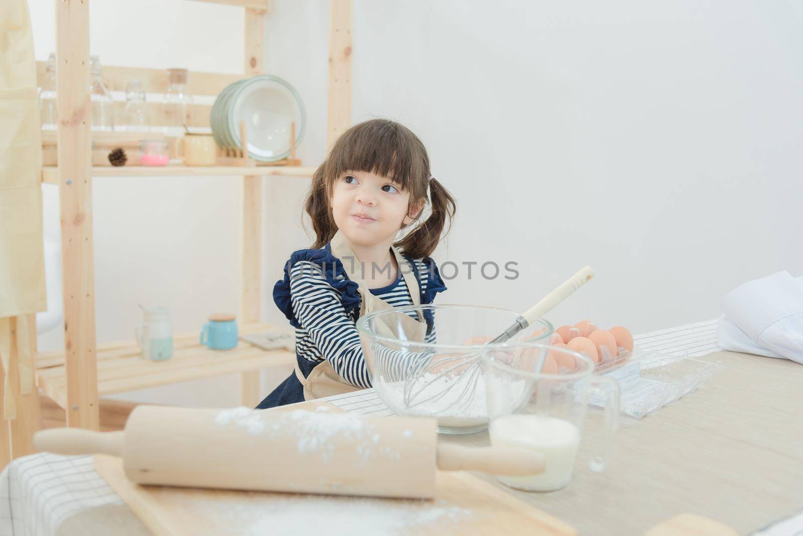 Asian children waiting her mother for preparing the dough to make a cake in the kitchen room on vacation.Photo series of Happy family concept.