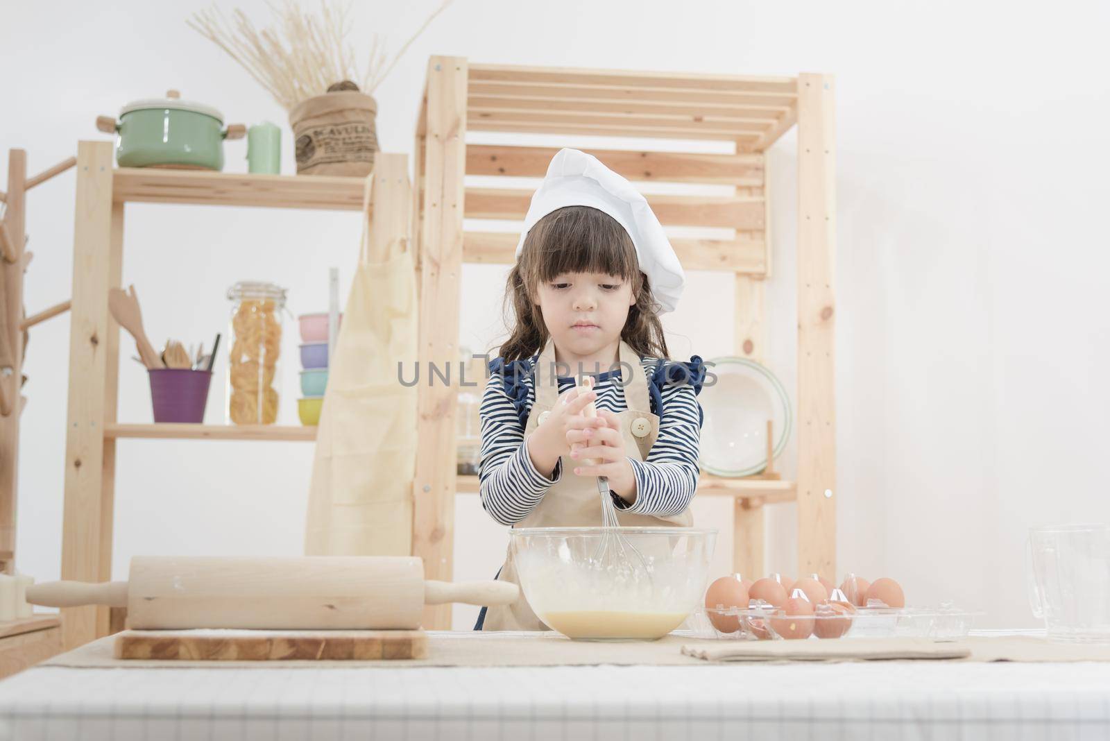 Cute kid enjoy preparing the dough to make a cake in the kitchen room.Photo series of Happy family concept.