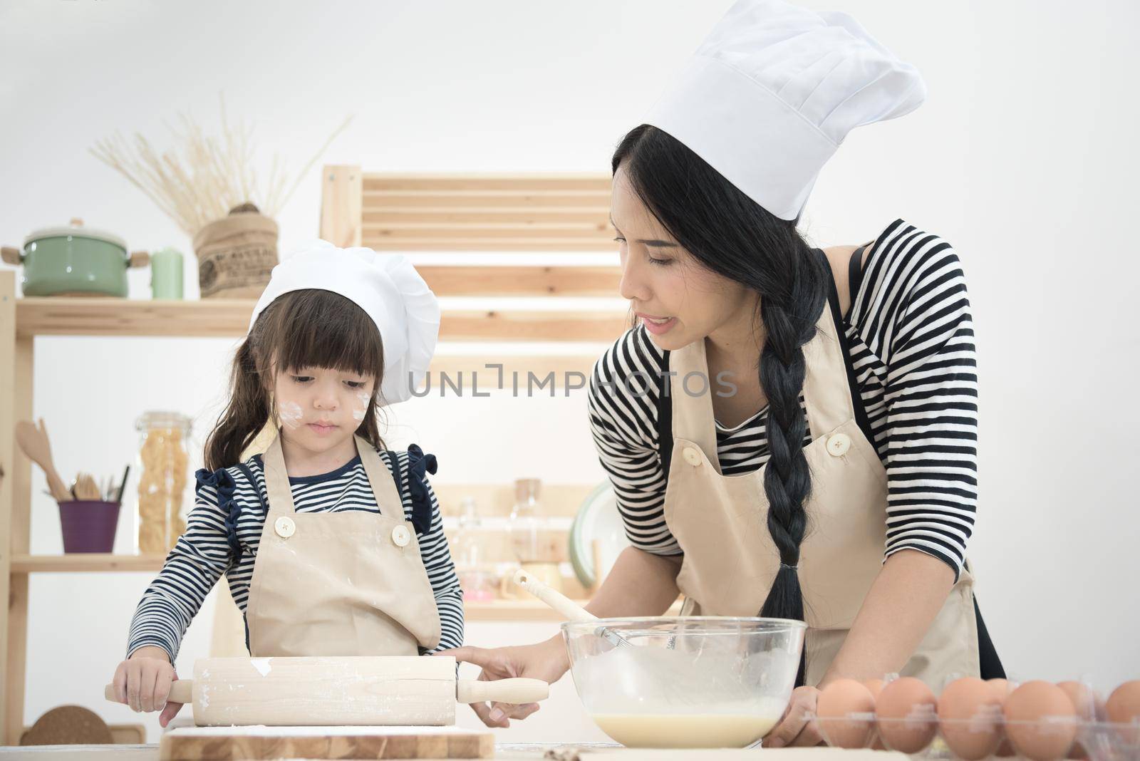Asian mother and her daughter are preparing the dough to make a cake in the kitchen room on vacation.Photo series of Happy family concept.