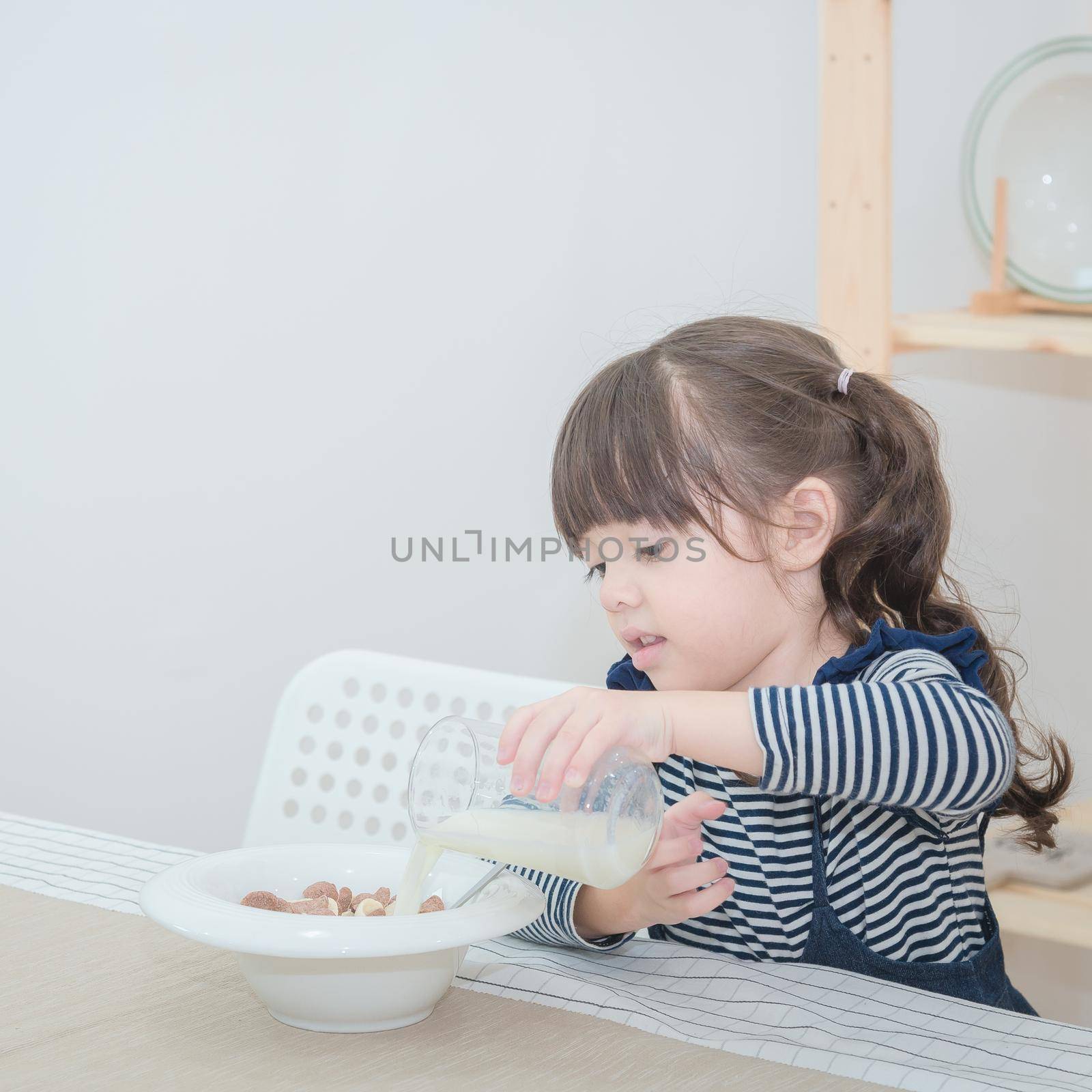 Happy cute little girl prepare healthy breakfast in the morning. Photo series of family, kids and happy people concept.