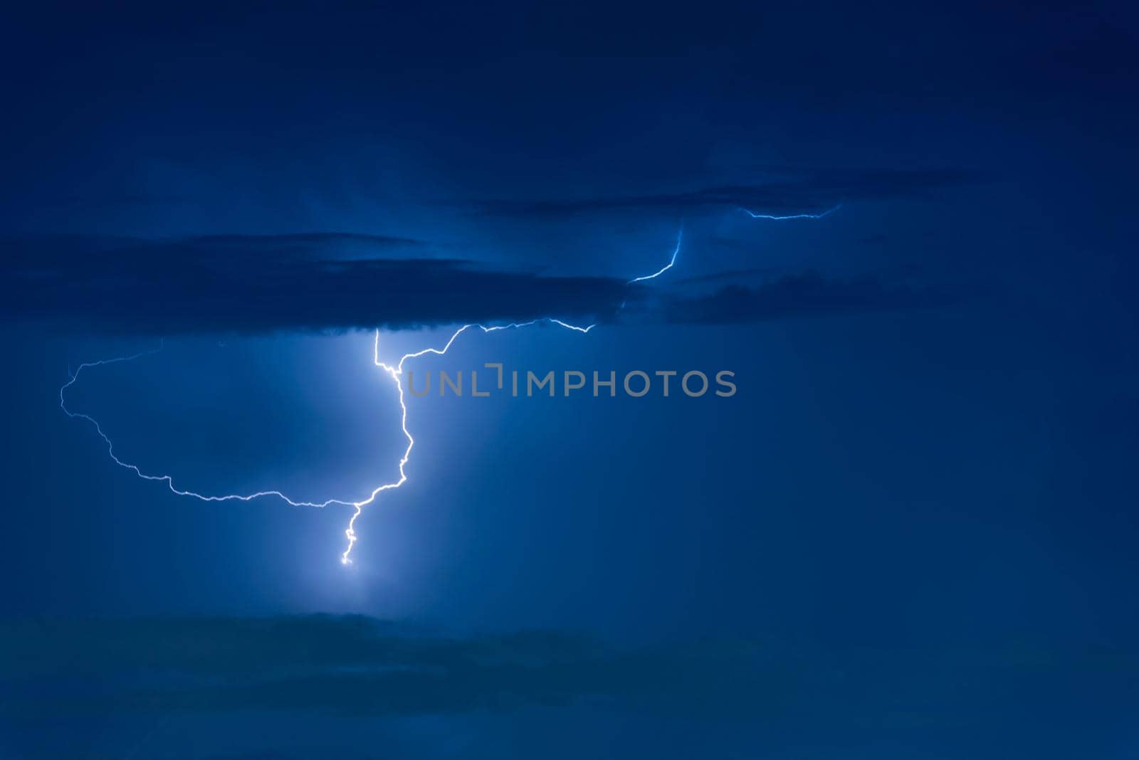 Thunder storm lightning strike on the dark cloudy sky background at night.