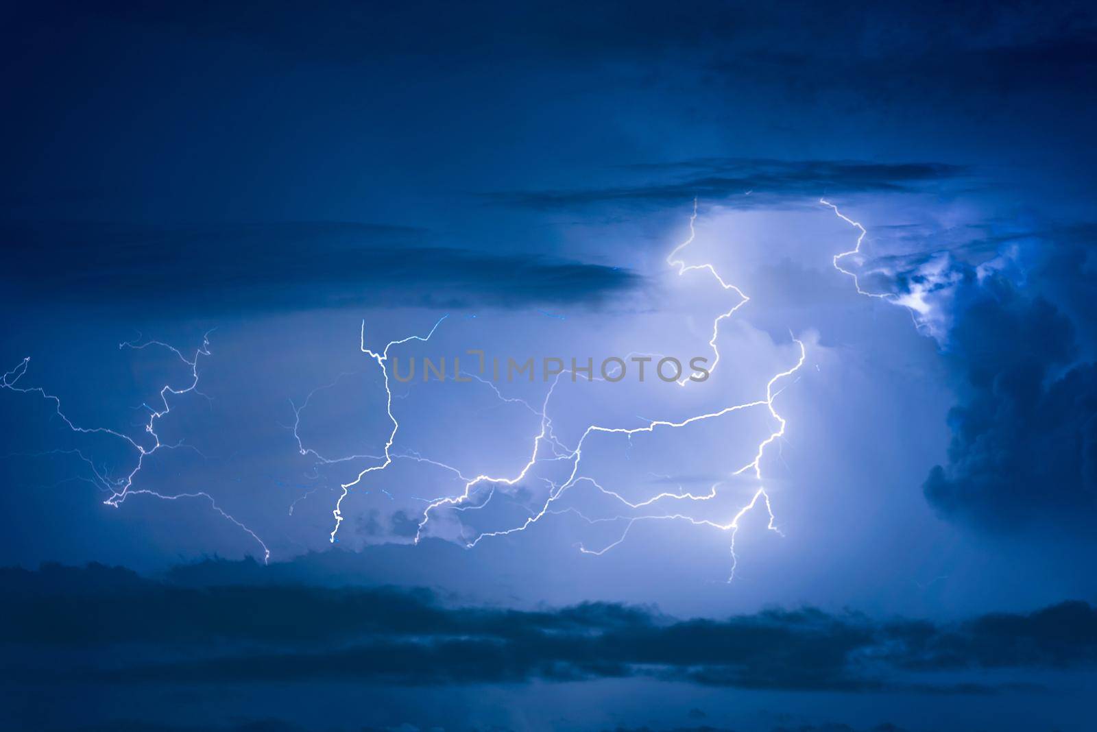 Thunder storm lightning strike on the dark cloudy sky background at night. by Nuamfolio