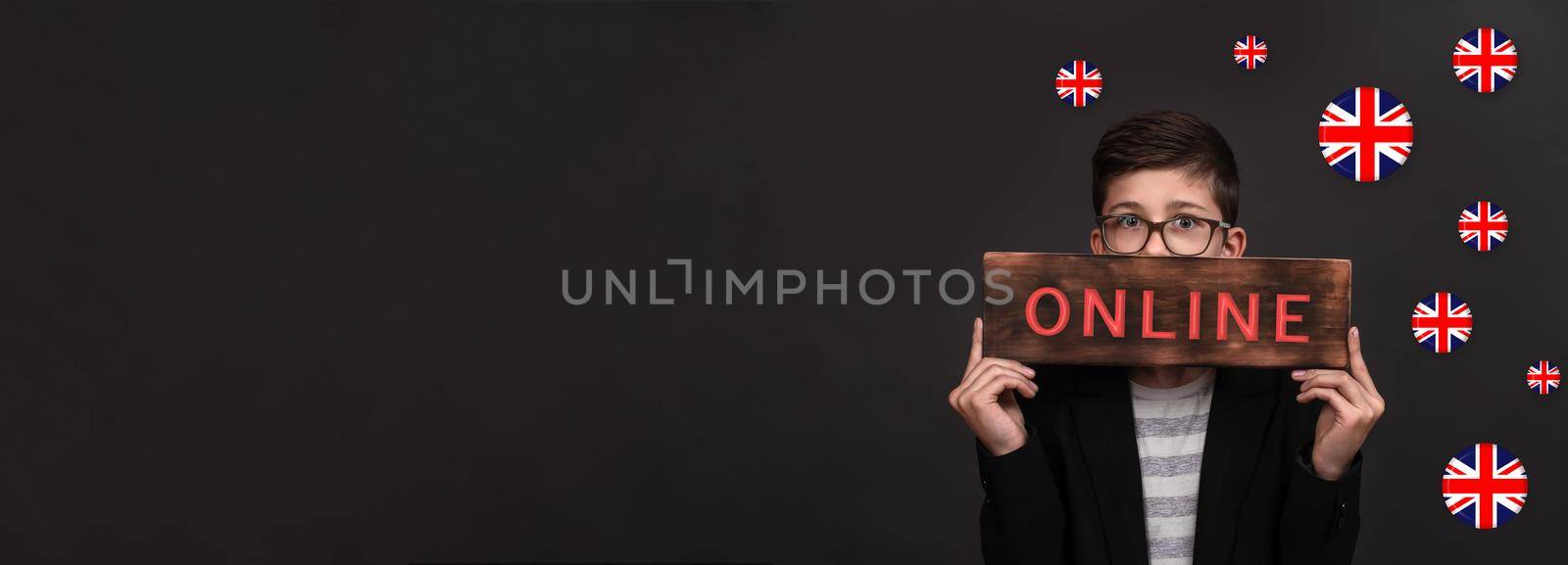 Online English language courses. Banner ad. A teenager holds a wooden sign with the inscription online, around the flags of England. copy space. black background