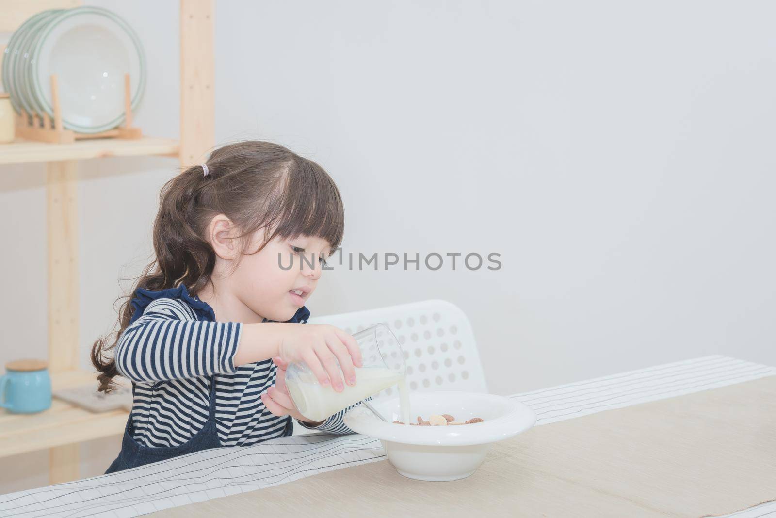Happy cute little girl prepare healthy breakfast in the morning. Photo series of family, kids and happy people concept.