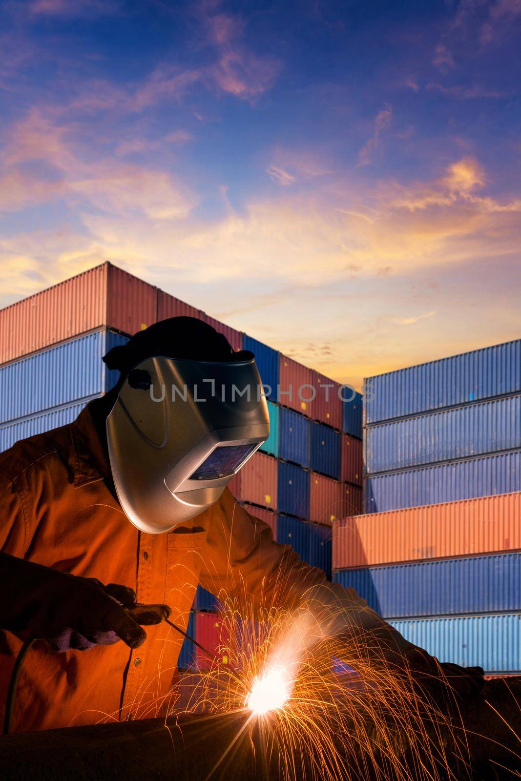 Industrial welding worker welding steel structure with cargo container stack in background for transportation, shipping and logistic industrial concept. by Nuamfolio