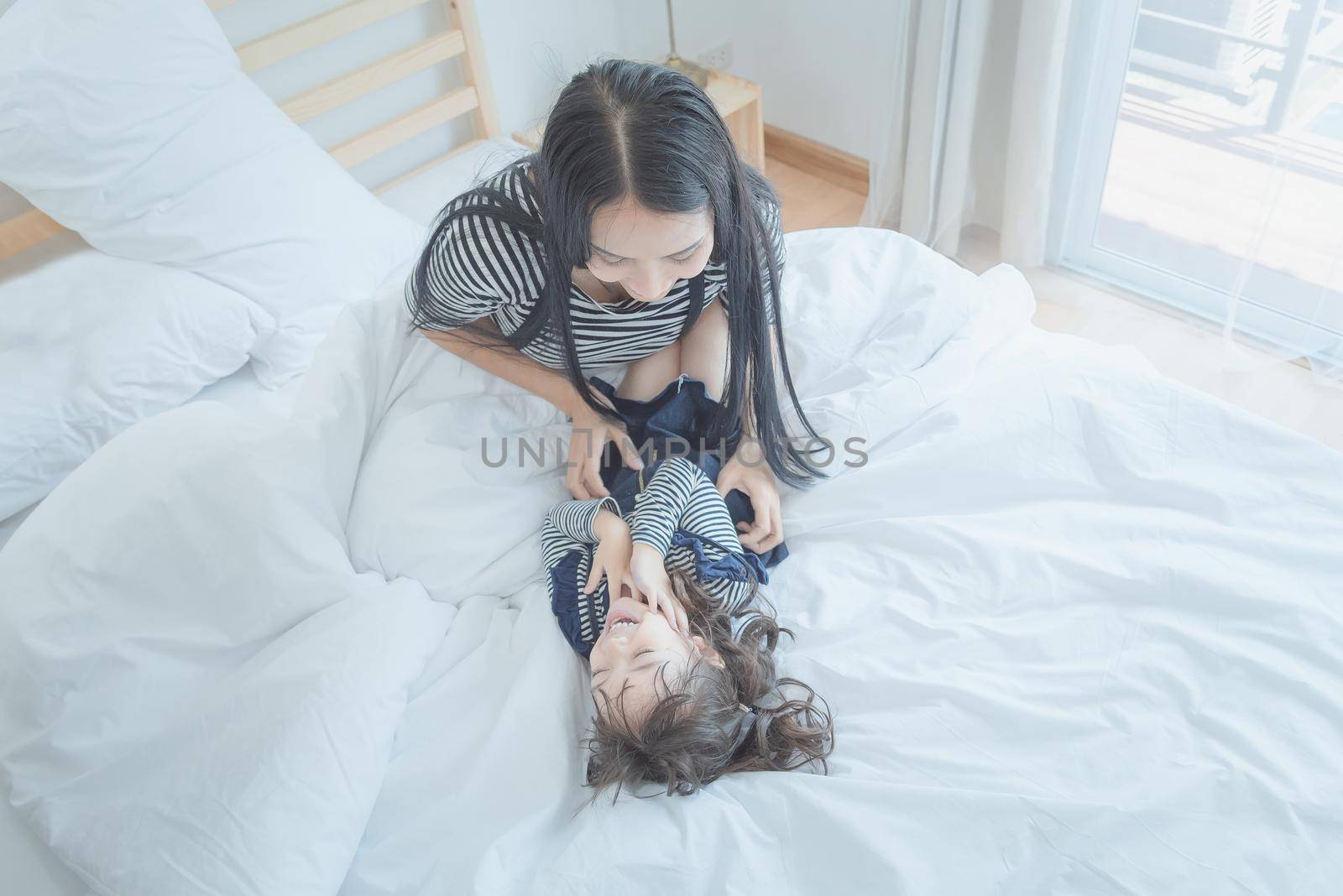 Happy loving family, Pretty young mother playing with her daughter in kid's room. by Nuamfolio