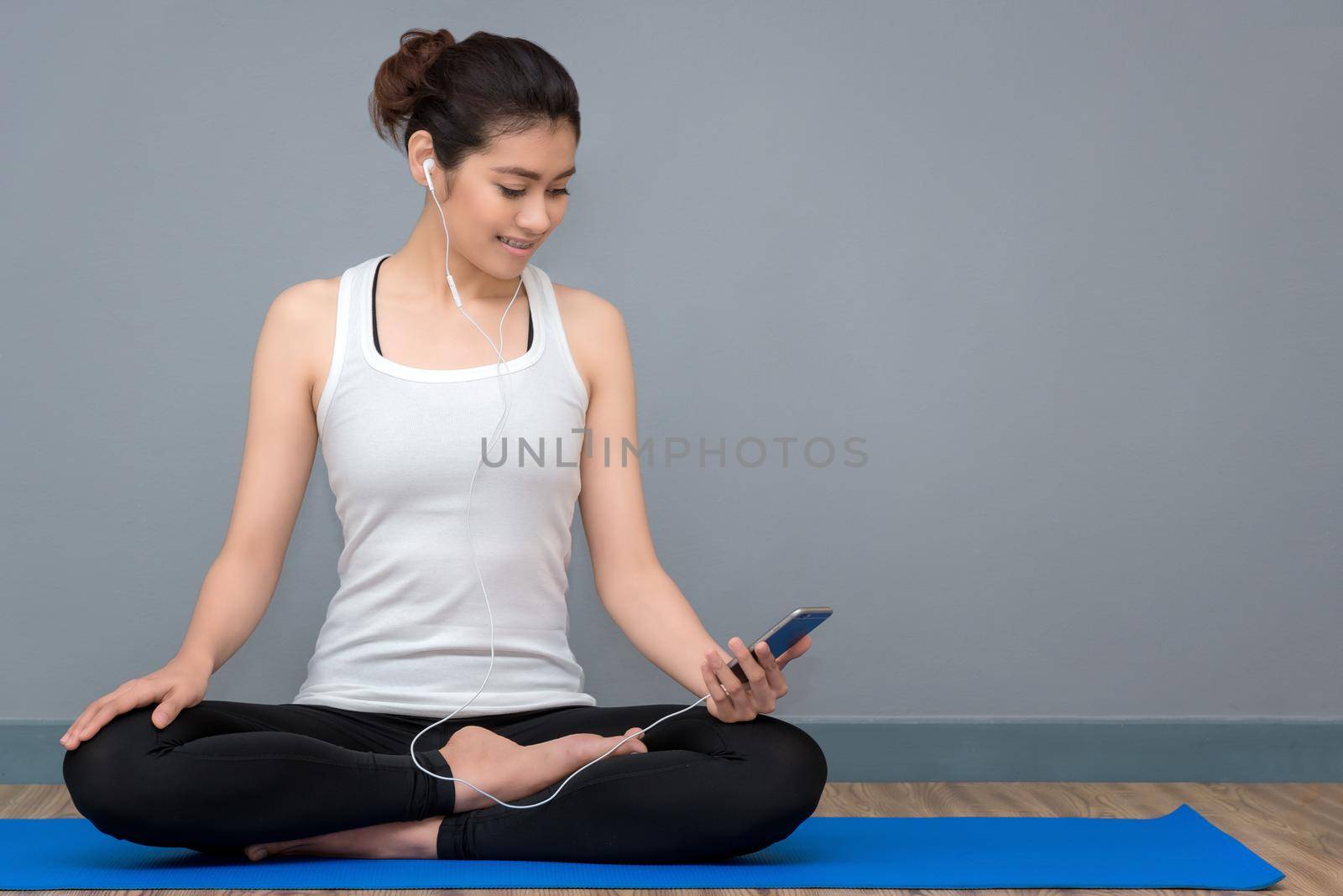 Young asian woman enjoy the music before practicing yoga at yoga healthy sport gym, yoga and meditation have good benefits for health. Photo concept for Yoga Sport and Healthy lifestyle by Nuamfolio