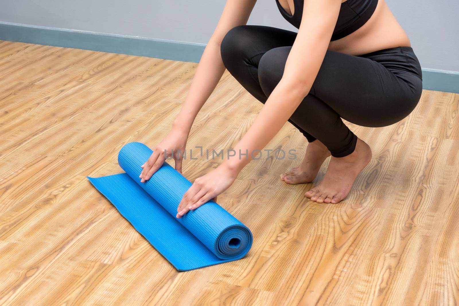 Young asian woman prepare her yoga mat at indoor yoga healthy sport gym. Yoga and meditation have good benefits for health. Photo concept for Yoga Sport and Healthy lifestyle. by Nuamfolio