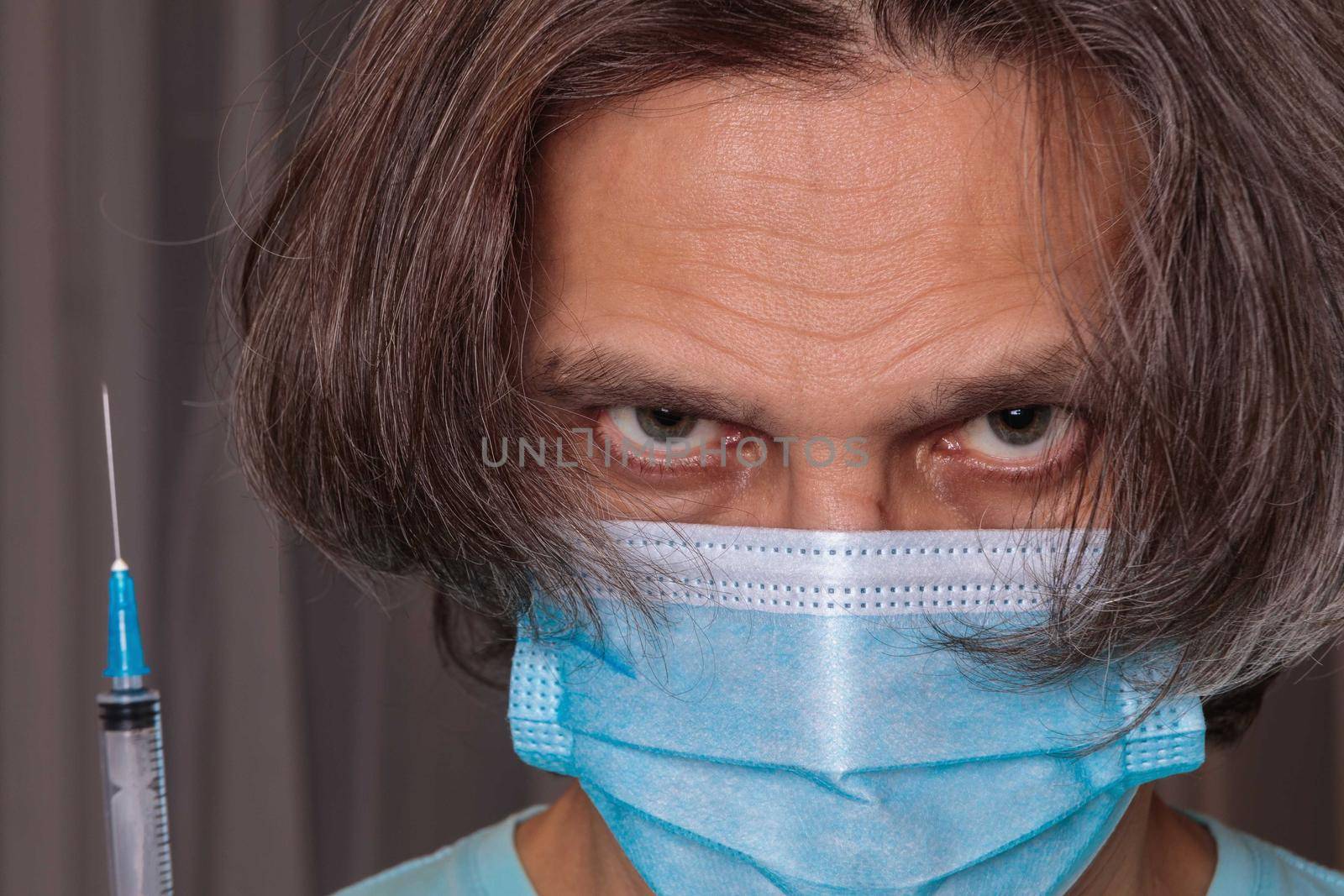 Adult man in a medical mask. Close-up eyes. Syringe in hand. Health safety concept