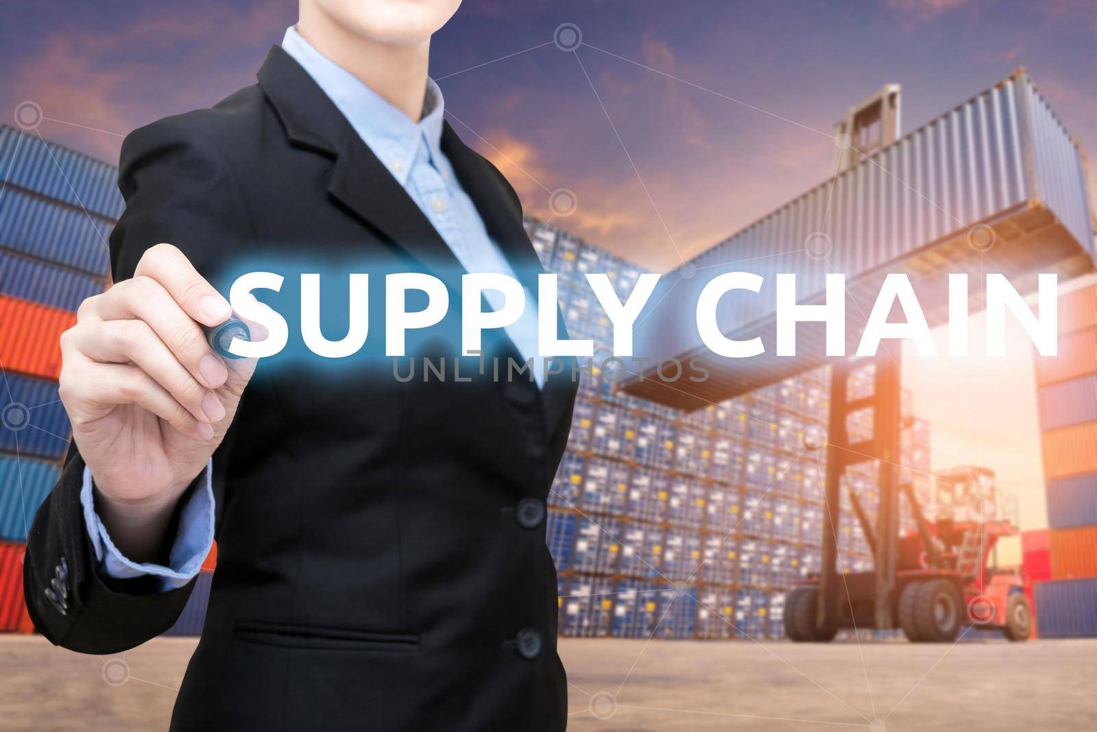 Smart business woman is writing Supply chain word with forklift lifting cargo container and cargo containers stack in background for global transportation import,export and logistic business concept by Nuamfolio