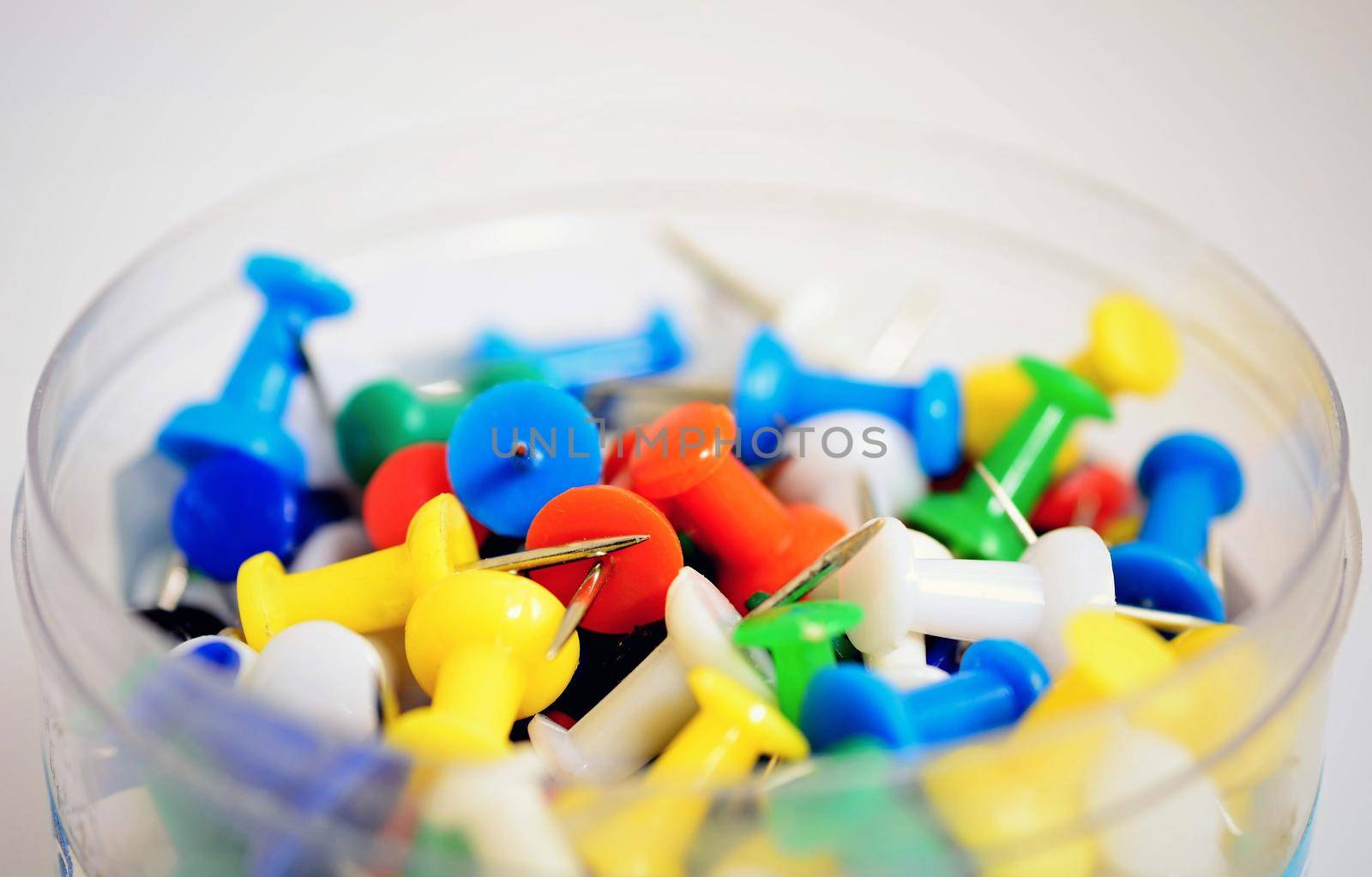 Heap of colorful office push pins on white background.