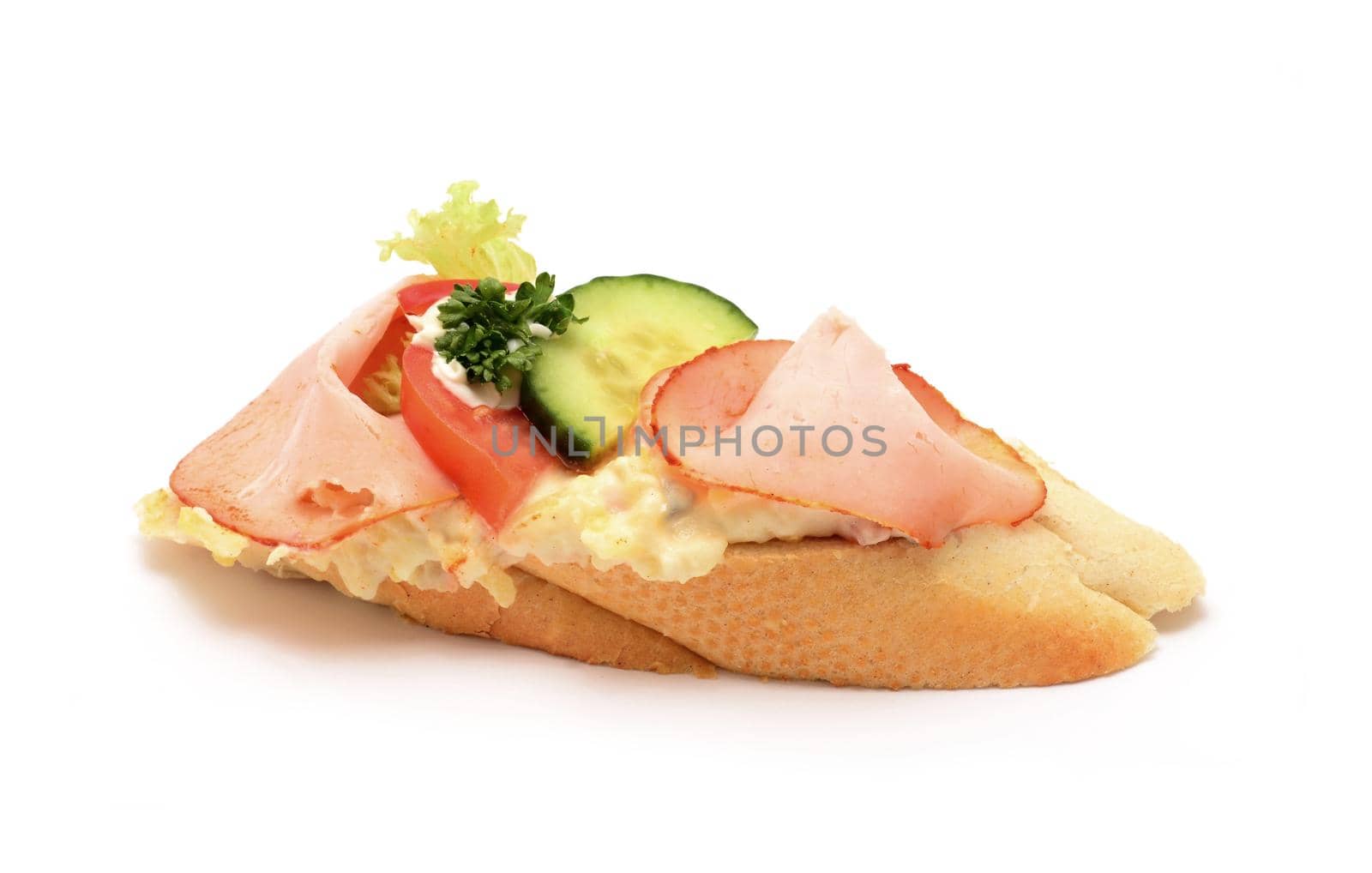 Traditional czech snack called chlebicek. Slices of ham, cucumber and tomato with mayonnaise decoratively laid on small soft white bread.