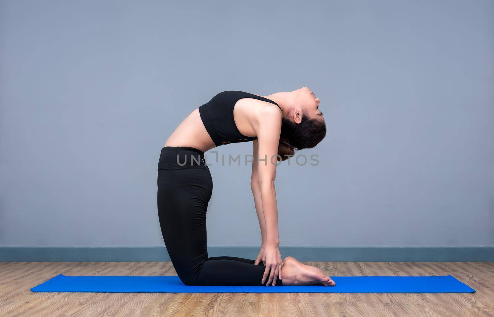 Young asian woman practicing yoga pose at yoga healthy sport gym, yoga and meditation have good benefits for health. Photo concept for Yoga Sport and Healthy lifestyle. by Nuamfolio