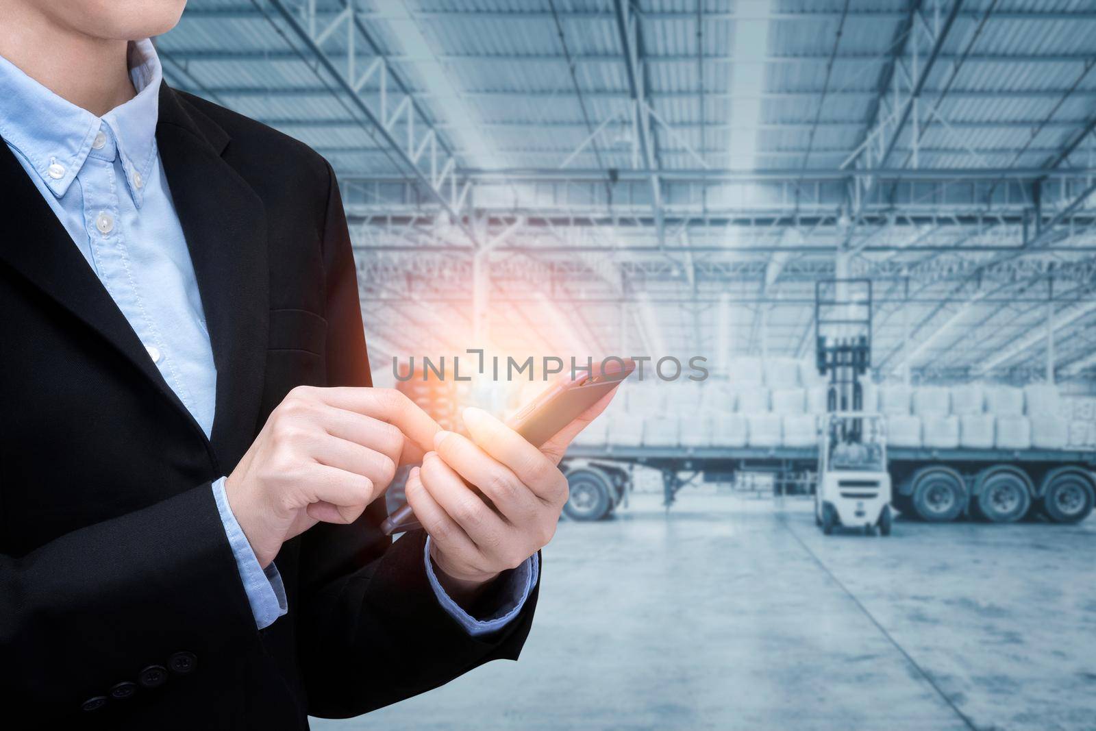 Smart Business woman use smartphone and internet of things technology with shipping warehouse in background for Global business shipping,Logistic,Import and Export business concept by Nuamfolio