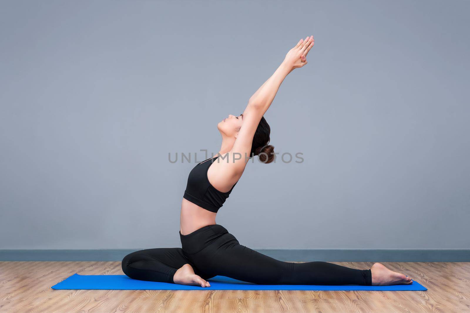 Young asian woman practicing yoga pose at yoga healthy sport gym, yoga and meditation have good benefits for health. Photo concept for Yoga Sport and Healthy lifestyle. by Nuamfolio