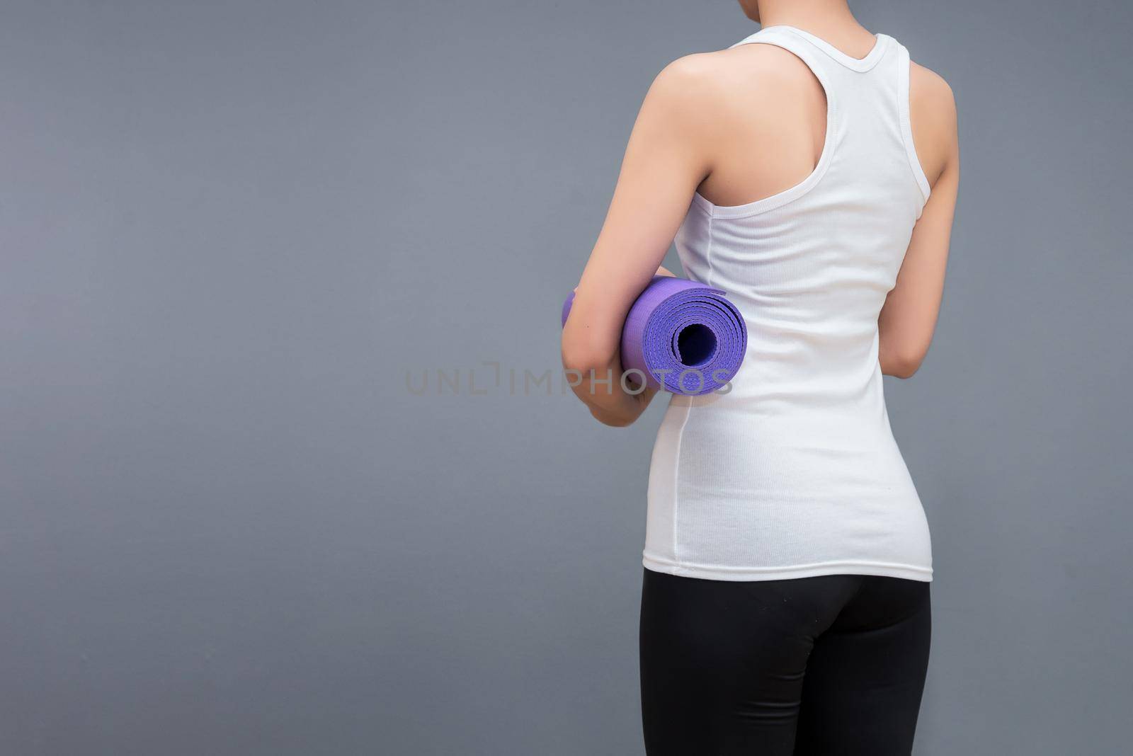 Young asian woman holding her yoga mat at yoga healthy sport gym. Yoga and meditation have good benefits for health. Photo concept for Yoga Sport and Healthy lifestyle. by Nuamfolio