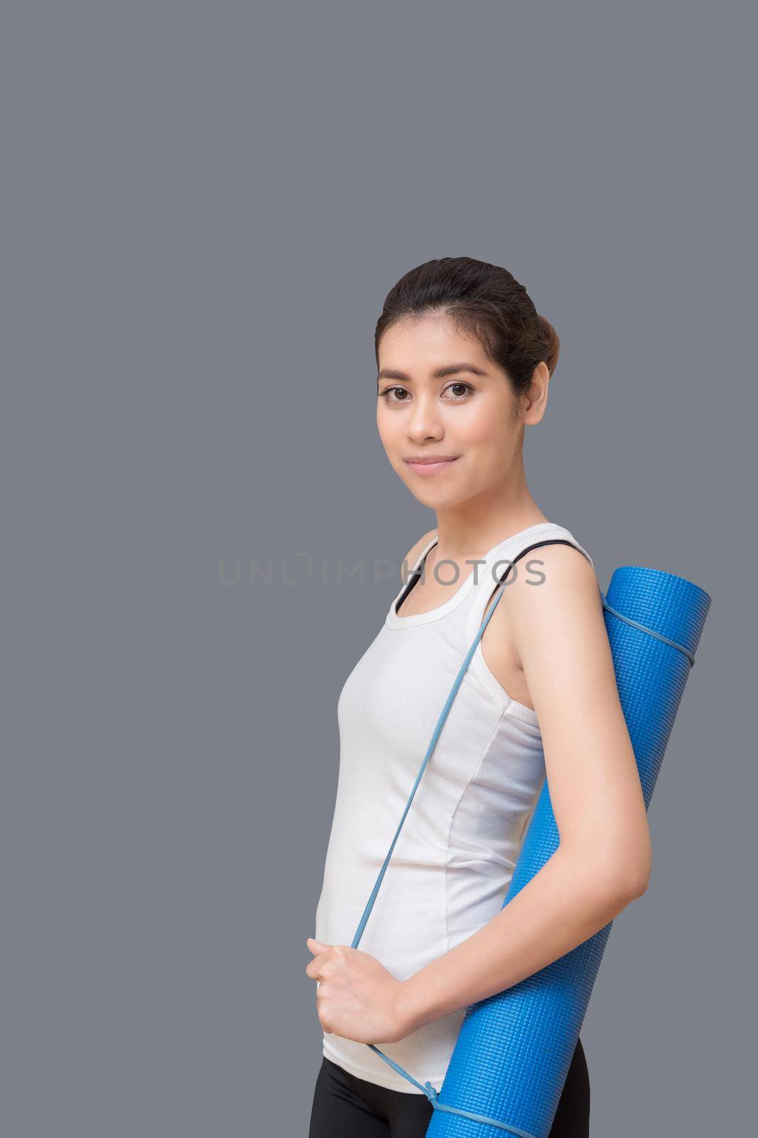 Young asian woman holding her yoga mat at yoga healthy sport gym. Yoga and meditation have good benefits for health. Photo concept for Yoga Sport and Healthy lifestyle by Nuamfolio