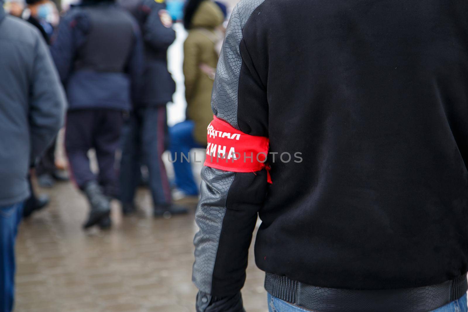 civillian man with red armband signed people's squad in russian - standing in crowd, close-up with selective focus and background blur