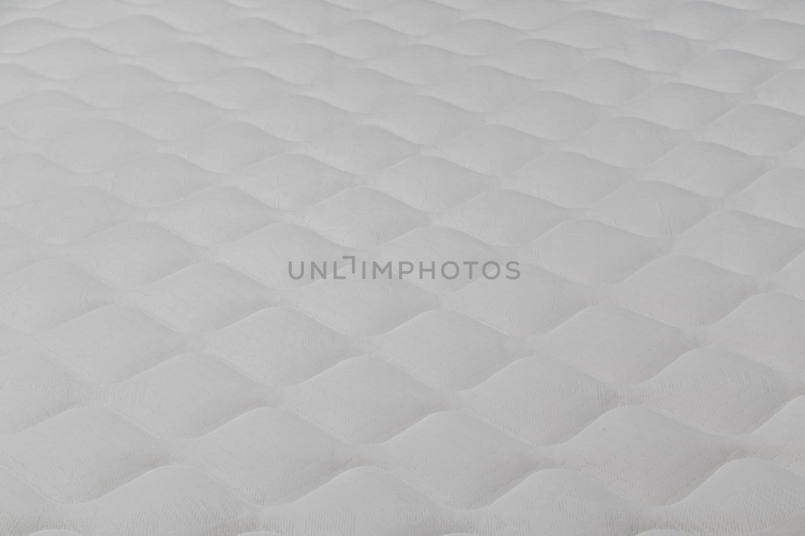 Soft white mattress close-up background with selective focus and blur.