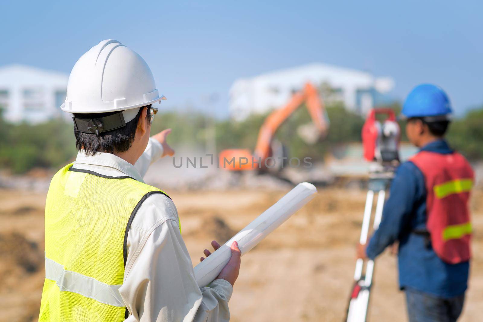 Construction engineer hodling construction drawing with foreman worker checking construction site by Nuamfolio