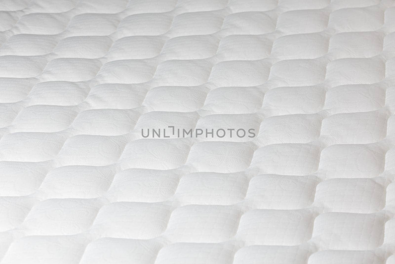 Soft white mattress close-up background with selective focus and blur.