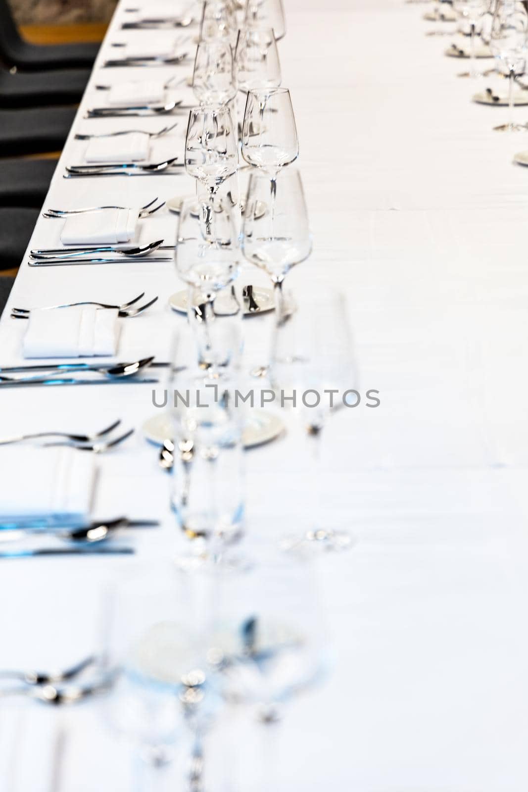 Long table with white tablecloth full of tableware prepared for lunch