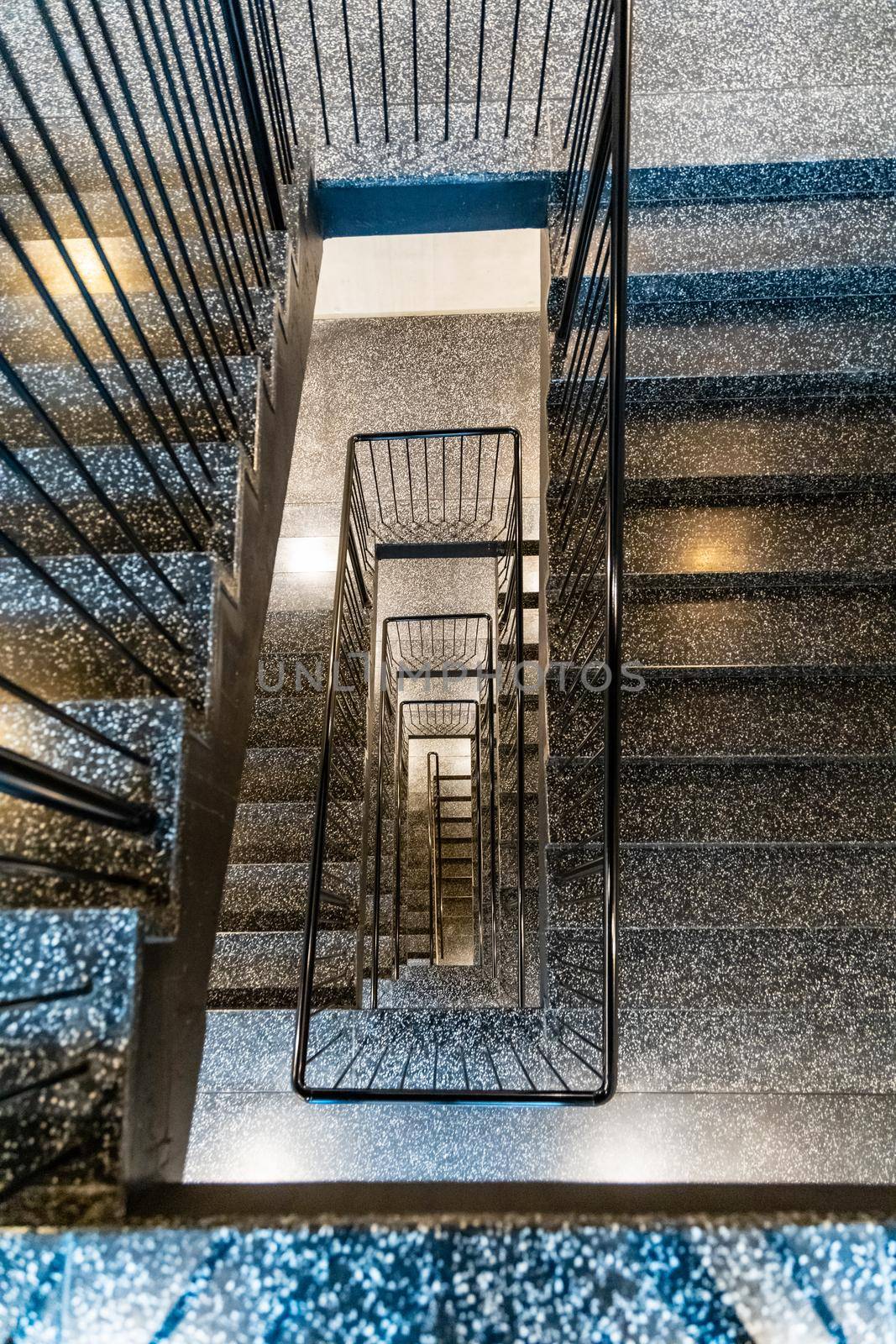 Top down view to rectangular spiral staircase with black metal railings