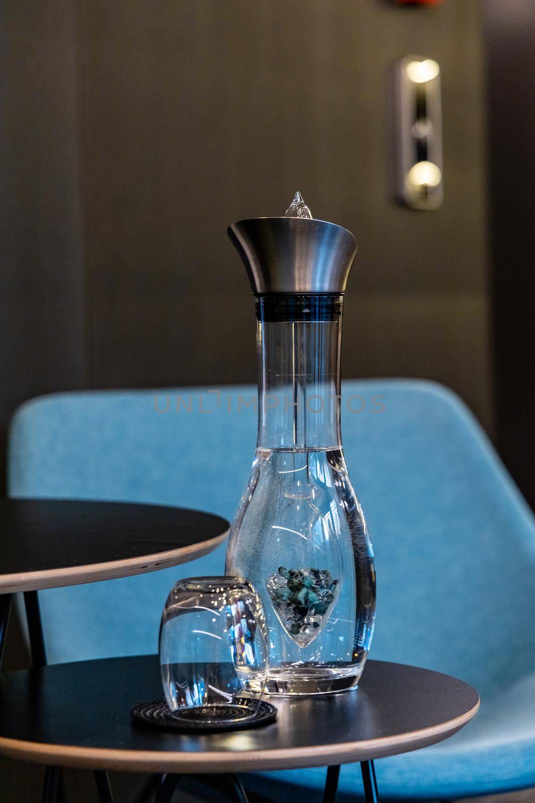 Small glass carafe full of water with blue and white crystals and glass by Wierzchu