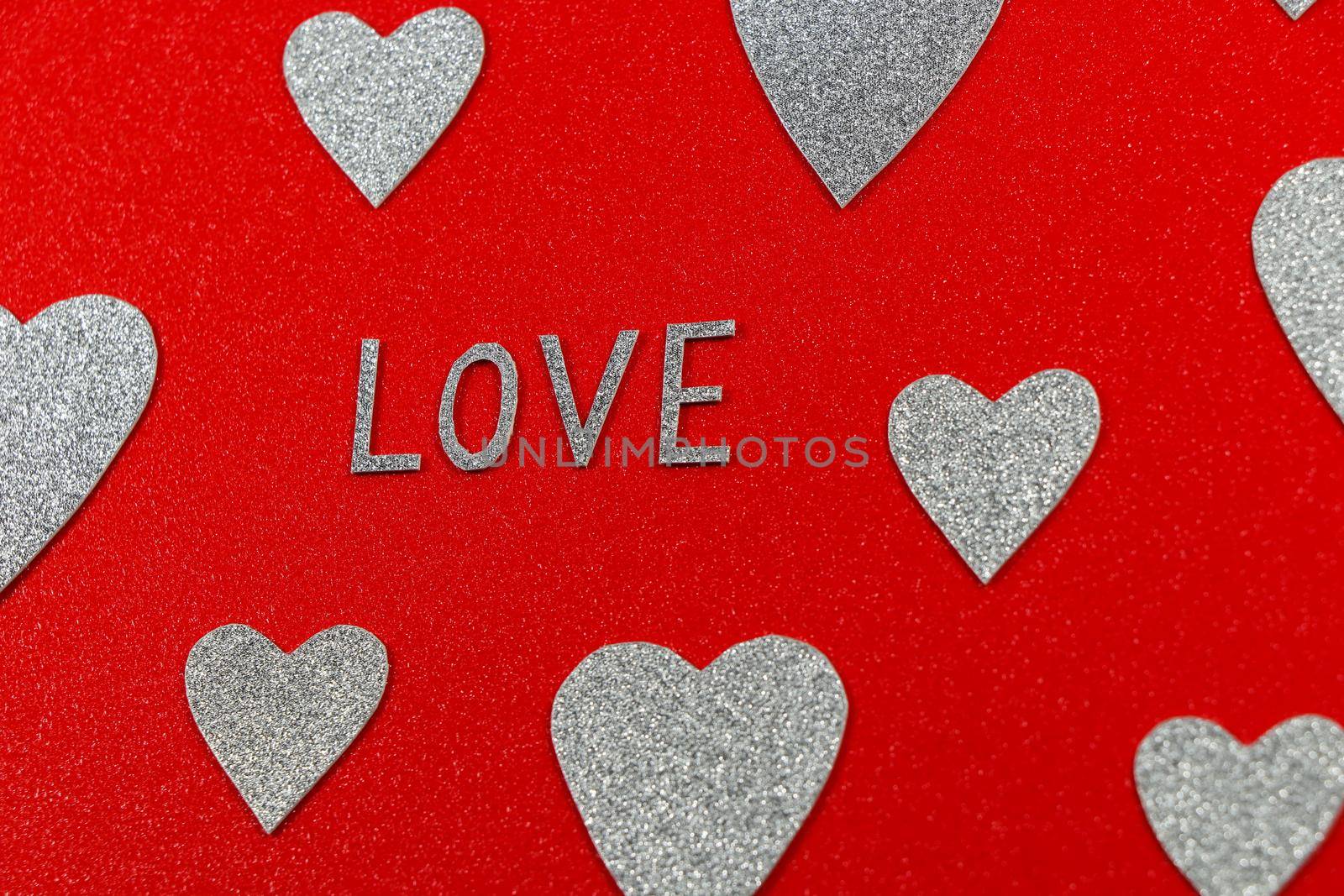 Saint Valentine's day love text and silver hearts design on red background abstract
