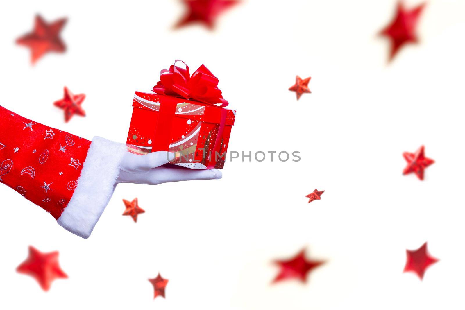 christmas santa claus hand with a present gift box  as a holiday season surprise  with red costume  and white gloves , isolated on background with stars falling and noel hand