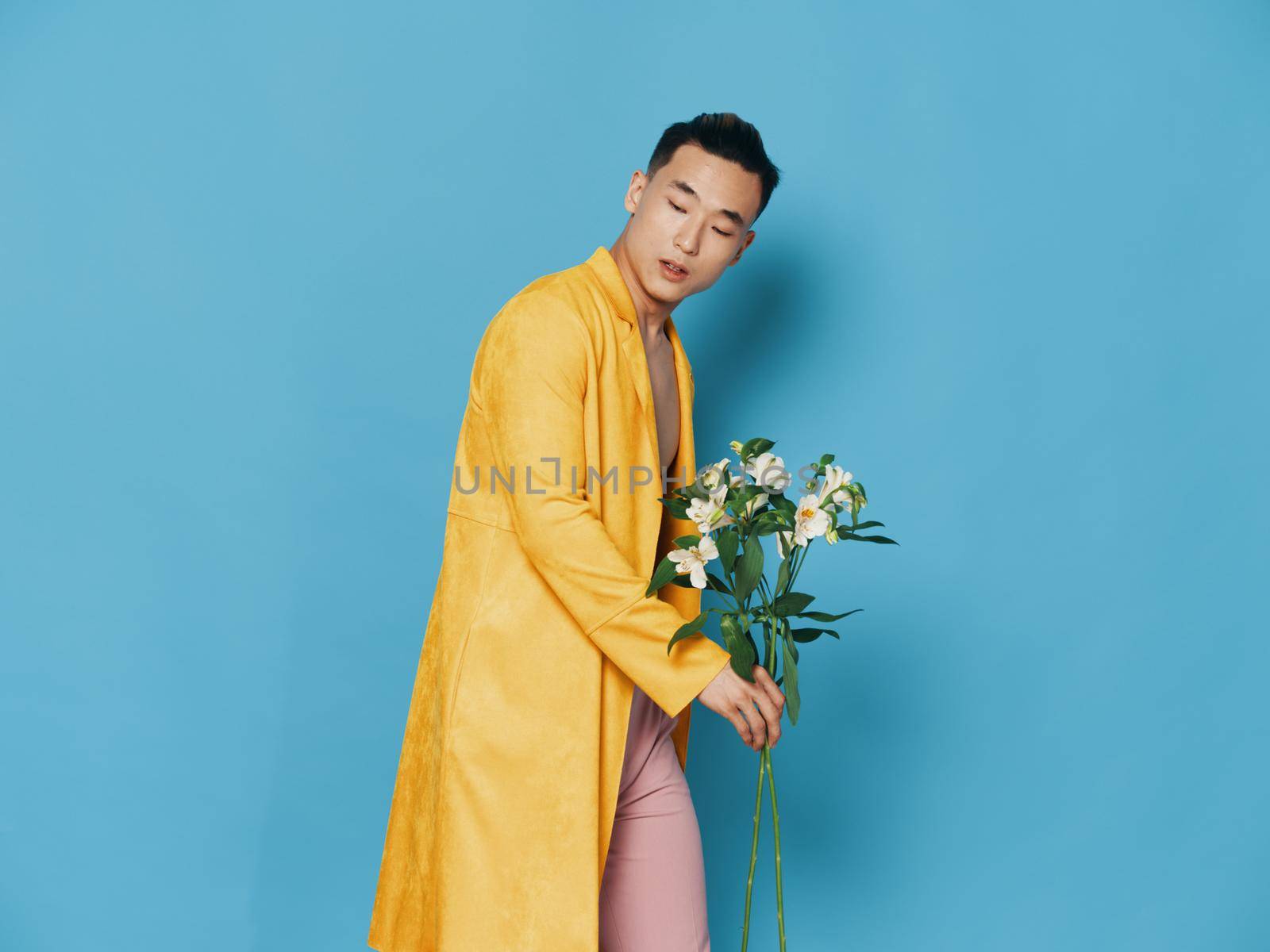 man in yellow coat with bouquet of white flowers blue background by SHOTPRIME