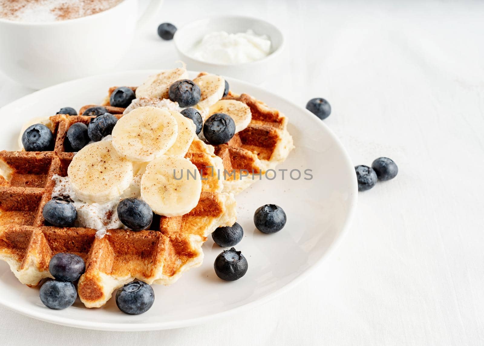 High angle view of fresh made waffles with blueberries, banana and yoghurt by Desperada