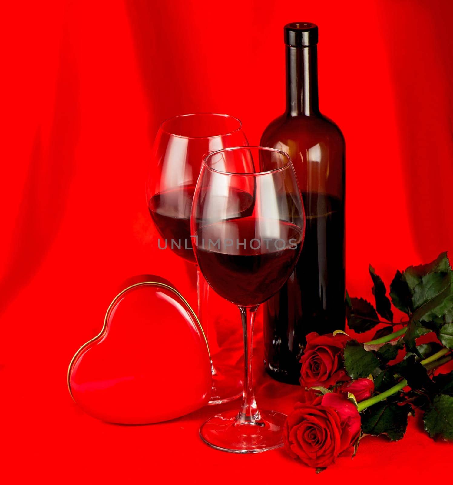 Valentine's Day. Gift box, flowers, glasses with wine and candy in the form of a heart on a red background by aprilphoto