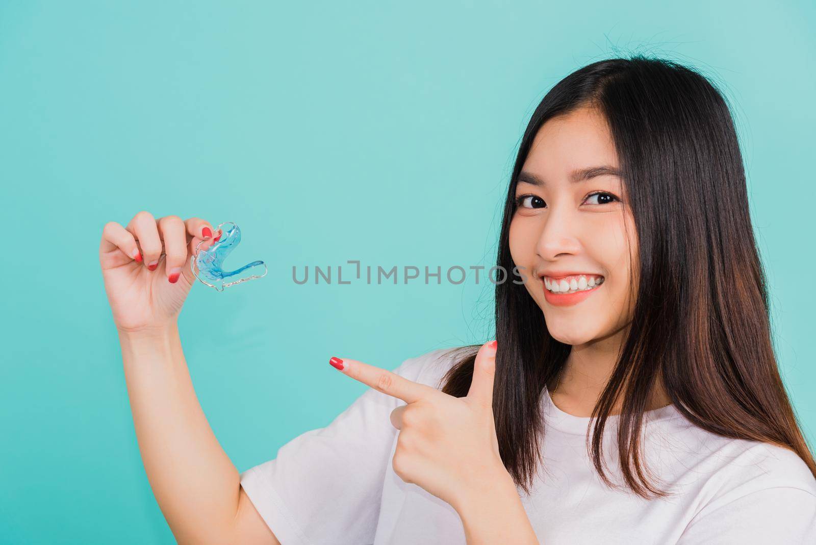 Portrait young Asian beautiful woman smiling pointing with finger silicone orthodontic retainers for teeth, Female hold teeth retaining tools after removable braces, Orthodontics dental care concept