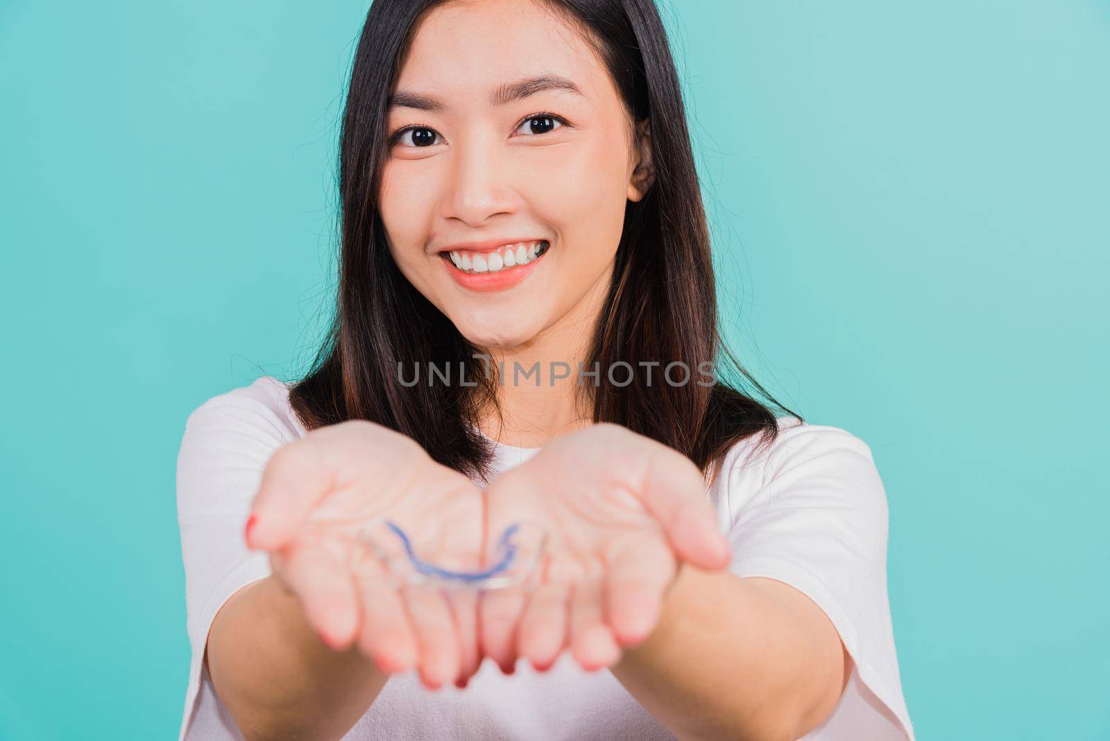 Portrait young Asian beautiful woman smiling holding silicone orthodontic retainers for teeth on hand palm, Teeth retaining tools after removable braces, Orthodontics dental healthy care concept